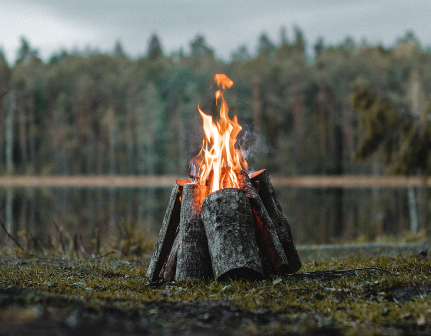 An evening campfire beside a lake at a Pelagus retreat