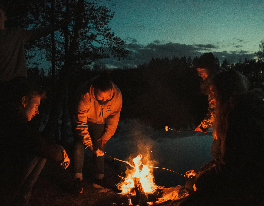 A group campfire by the water at dusk