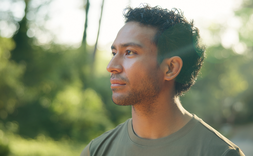 A person pausing while hiking in an Irish woodland, surrounded by trees in soft natural light